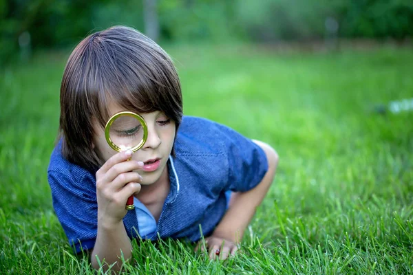 Preteen child, boy, exploring with magnifying glass, watching la — Stock Photo, Image