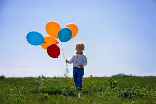 Niño pequeño, niño pequeño, niño jugando con globos de colores en el — Foto de Stock