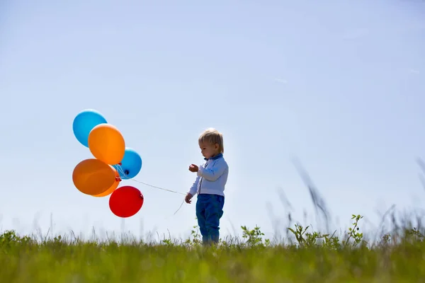 Маленький хлопчик, малюк, дитина грає з різнокольоровими кульками в — стокове фото