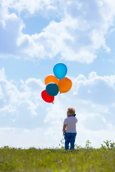 Niño pequeño, niño pequeño, niño jugando con globos de colores en el — Foto de Stock