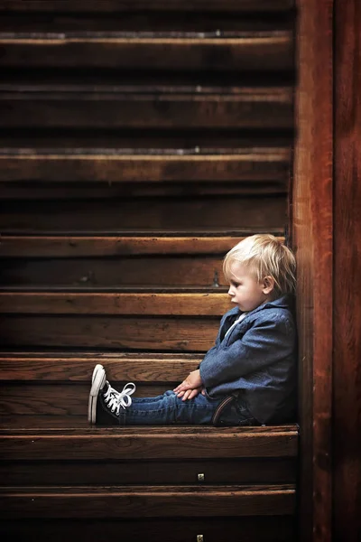 Triest kind, zittend op een trap in een groot huis, concept voor Bu — Stockfoto