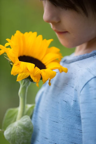 Ragazzo che tiene il fiore in mano su sfondo verde. App europea — Foto Stock