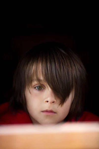 Προεφηβικό αγόρι με κόκκινο φούτερ, κρυμμένο πίσω από μια ξύλινη πόρτα, κοίτα — Φωτογραφία Αρχείου