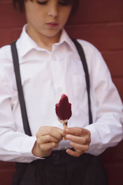 Симпатична дитина, хлопчик у вінтажному одязі, їсть льодяне морозиво, сі — стокове фото