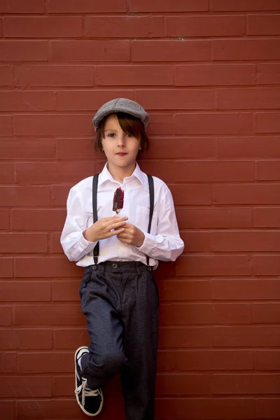 Niedliches Kind, Junge in Vintage-Tüchern, essen Lutscher-Eis, si — Stockfoto