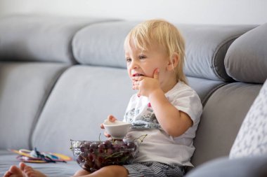 Tatlı Toddler çocuk, bir kanepede oturan, kiraz ve Looki yeme