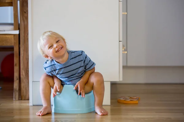 Petit garçon tout-petit, assis sur un pot, jouant avec un jouet en bois — Photo