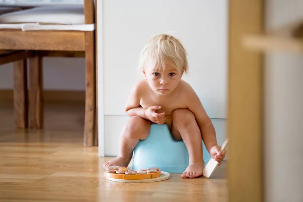 小蹒跚学步的男孩,坐在便盆上,玩木制玩具 — 图库照片