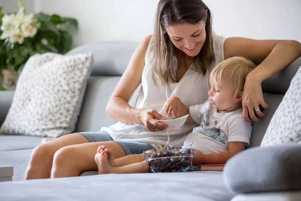 Dolce bambino ragazzo e sua madre, seduto su un divano, mangiare che — Foto Stock