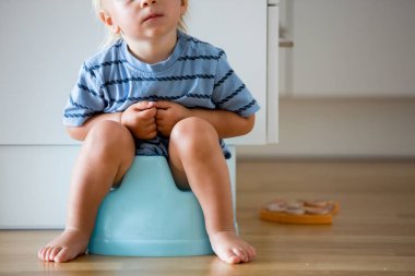 Küçük Toddler çocuk, tuvalete oturan, ahşap oyuncak ile oynuyor