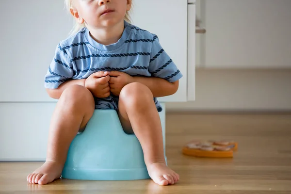 Little småbarn pojke, sitter på potta, leker med trä leksak — Stockfoto