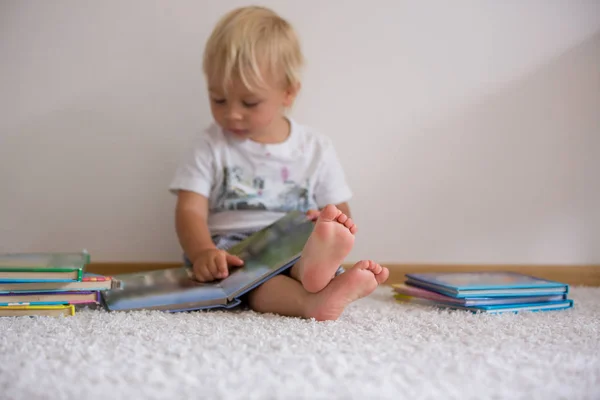 Sweet toddler boy, reading book at home, sitting on the ground, — Stock Photo, Image
