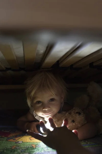 어린 아이, 침대 아래에 숨어, 테디 베어와 홀디를 껴안고 — 스톡 사진