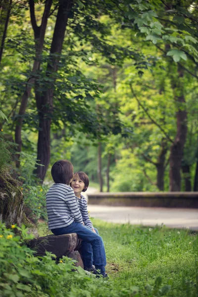 Dulces hermanos gemelos, niños sentados en el banco en el parque —  Fotos de Stock