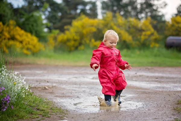 Süßer kleiner Junge, blondes Kind in rotem Regenmantel und blauem Hemd — Stockfoto