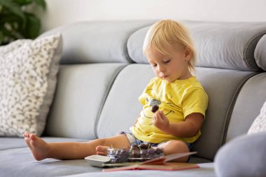 Tatlı Toddler çocuk, bir kanepede oturan, kiraz ve Looki yeme
