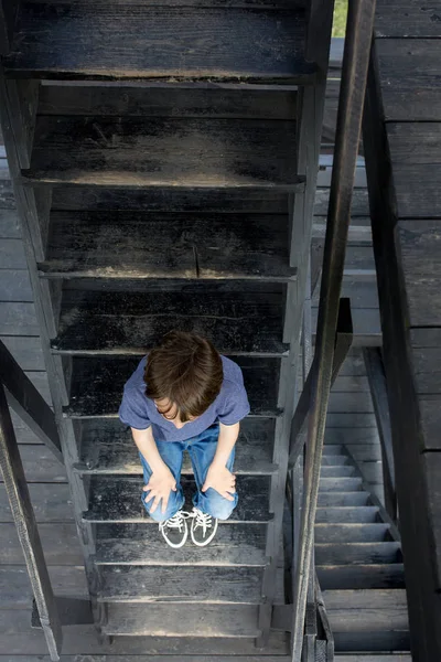 Barn, preteen pojke, sitter på trätrappor — Stockfoto