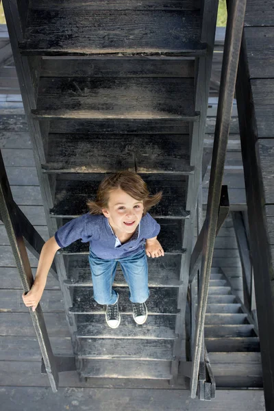 Criança, menino pré-adolescente, sentado em escadas de madeira — Fotografia de Stock
