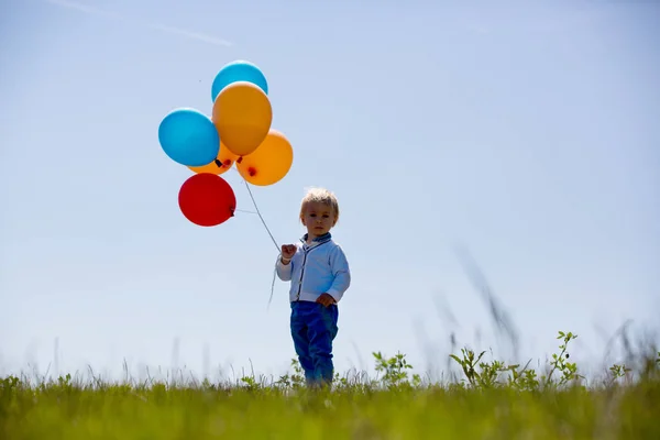 Niño pequeño, niño pequeño, niño jugando con globos de colores en el — Foto de Stock