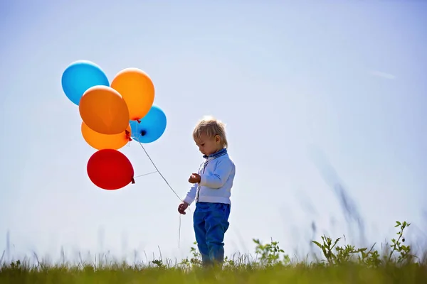 Petit garçon, tout-petit, enfant jouant avec des ballons colorés dans le — Photo