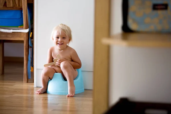 小さな幼児の男の子、トイレに座って、木製のおもちゃで遊んで — ストック写真