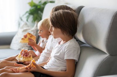 Sevimli çocuklar, kanepede oturan, pizza yemek ve Tv izlerken.