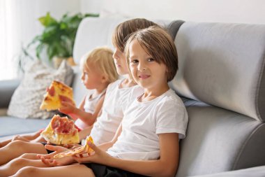 Sevimli çocuklar, kanepede oturan, pizza yemek ve Tv izlerken.