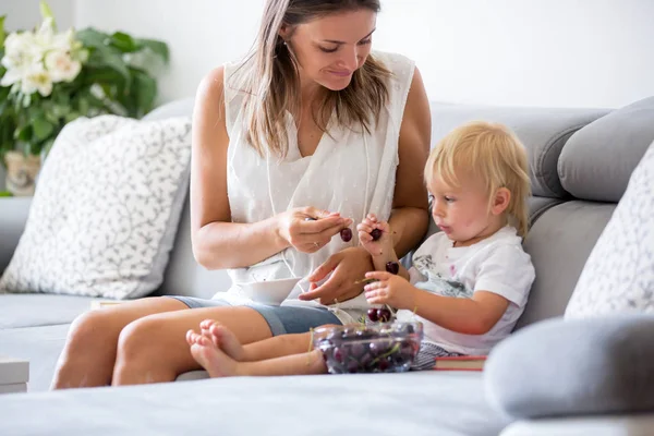 Dolce bambino ragazzo e sua madre, seduto su un divano, mangiare che — Foto Stock