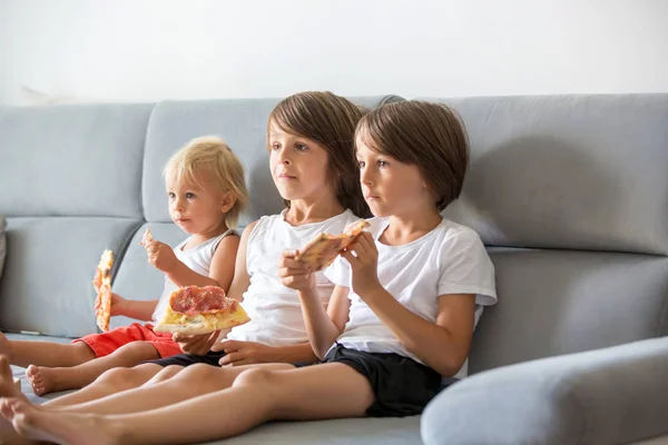 Leuke kinderen, zittend op de Bank, pizza eten en tv kijken. H — Stockfoto