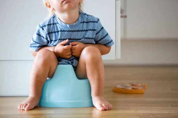 Little småbarn pojke, sitter på potta, leker med trä leksak — Stockfoto