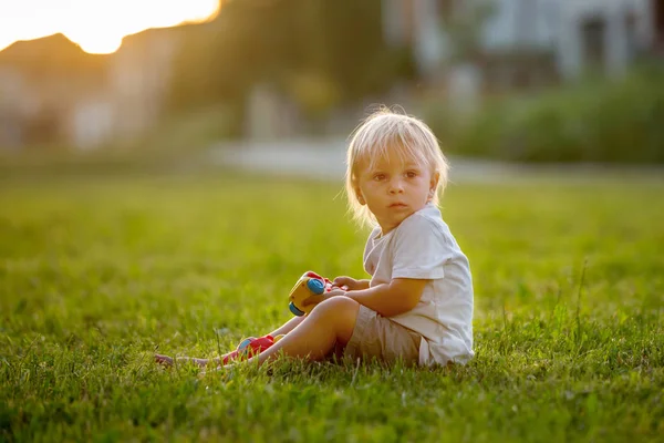 Schönes Kleinkind, das mit Plastikspielzeug, Bauklötzen, Autos spielt — Stockfoto