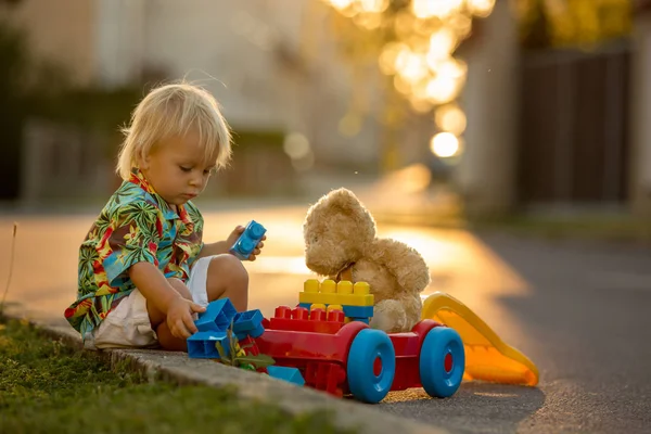 Schönes Kleinkind, das mit Plastikspielzeug, Bauklötzen, Autos spielt — Stockfoto