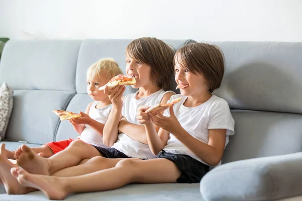 Nette Kinder, die auf der Couch sitzen, Pizza essen und fernsehen. h — Stockfoto