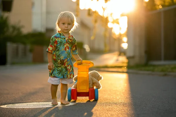 Schönes Kleinkind, das mit Plastikspielzeug, Bauklötzen, Autos spielt — Stockfoto