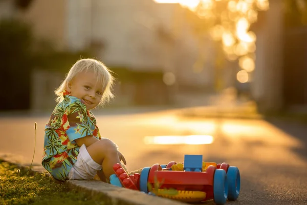 Hermoso niño pequeño, jugando con juguetes de plástico, bloques, coches —  Fotos de Stock