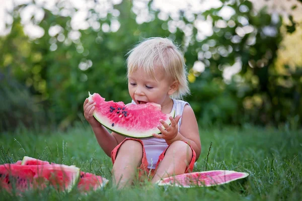 Niedliches Kleinkind, kleiner Junge, isst reife Wassermelone im Garten — Stockfoto