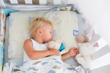 Gündelik giysiler içinde Tatlı bebek çocuk, teddy bea ile yatakta uyku