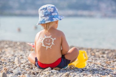 Tatlı okul öncesi çocuk, sunscream uygulanan tüplü maske tutarak o