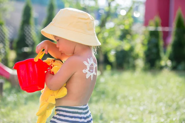 Niño pequeño con loción bronceadora en forma de sol en su espalda, goin — Foto de Stock