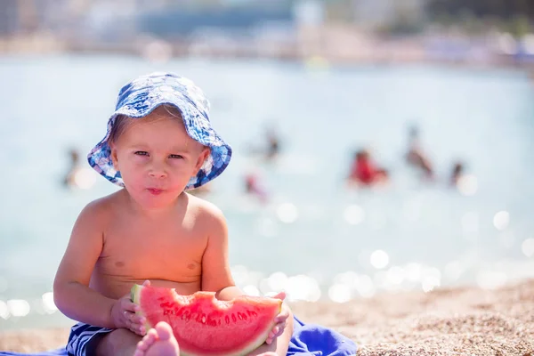 Lindo niño, niño rubio, comer sandía en la playa co — Foto de Stock