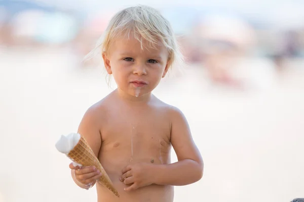 Édes szőke kisgyermek fiú, eaiting fagylaltot a strandon — Stock Fotó