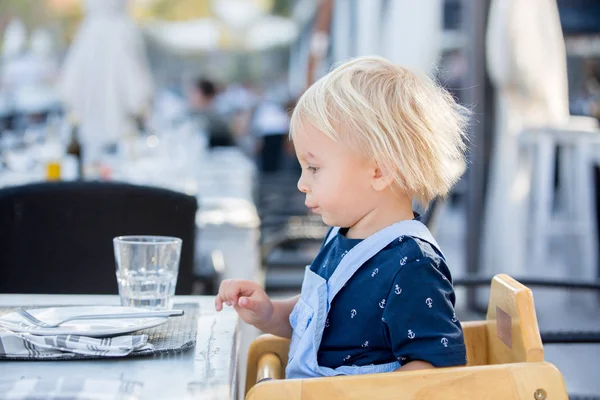 Niedliche Kleinkind Junge, sitzt im Hochstuhl in einem Restaurant, trinkt — Stockfoto