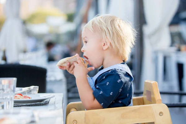 Χαριτωμένο νήπιο Boy, καθισμένος σε καρεκλάκι σε ένα εστιατόριο, τρώγοντας — Φωτογραφία Αρχείου