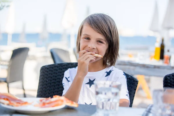可爱的学龄前男孩，坐在餐厅里，吃披萨 — 图库照片