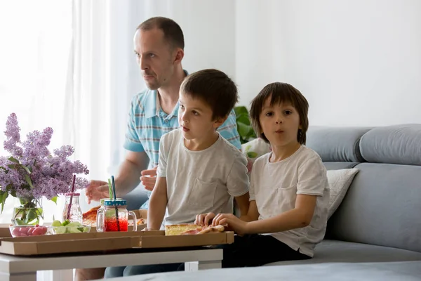 Pai e seus dois meninos, filhos, comendo pizza em casa e watc — Fotografia de Stock