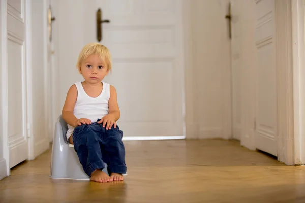 Criança infantil bebê menino criança sentado no penico, brincando com brinquedo — Fotografia de Stock