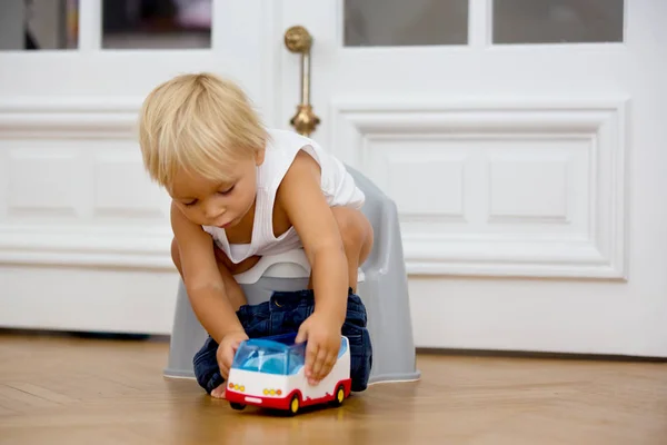 Criança infantil bebê menino criança sentado no penico, brincando com brinquedo — Fotografia de Stock