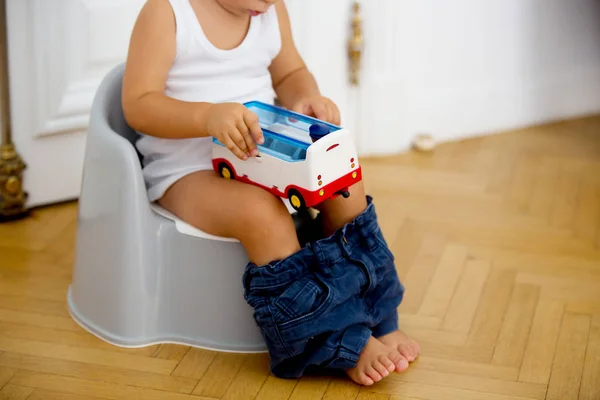 Niño bebé niño pequeño sentado en el orinal, jugando con el juguete —  Fotos de Stock