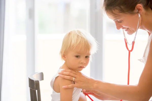 Dokter anak sedang memeriksa bayi laki-laki. Dokter menggunakan stetoskop ke lis — Stok Foto