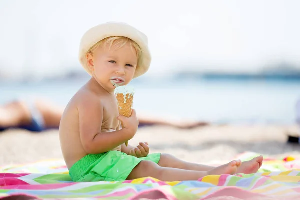 Zoete blonde peuter jongen, eaiting ijs op het strand — Stockfoto
